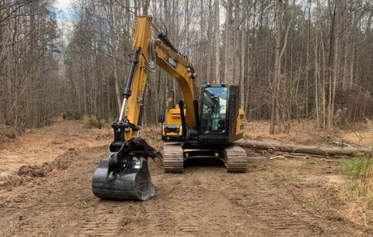 A caterpillar excavator in a wooded area.