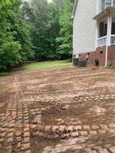 A dirt driveway with a brick path in front of a house.