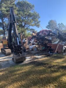 An excavator in front of a pile of debris.