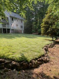A grassy yard with a stone wall in the middle.