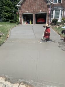 A man working on a concrete driveway in front of a house.