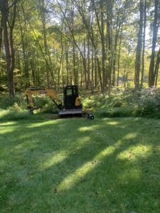 A small excavator in a wooded area.