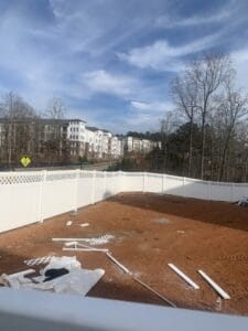 A white fence is being built in a backyard.