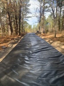 A black tarp covering a road in the woods.
