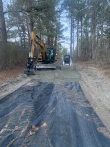 A construction crew is working on a road in the woods.
